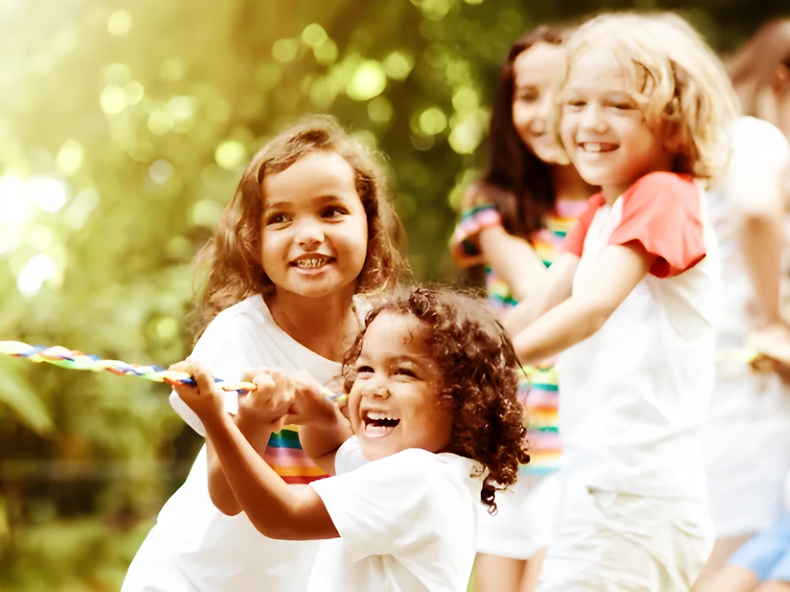 Lachende Kinder ziehen gemeinsam an einem Seil
