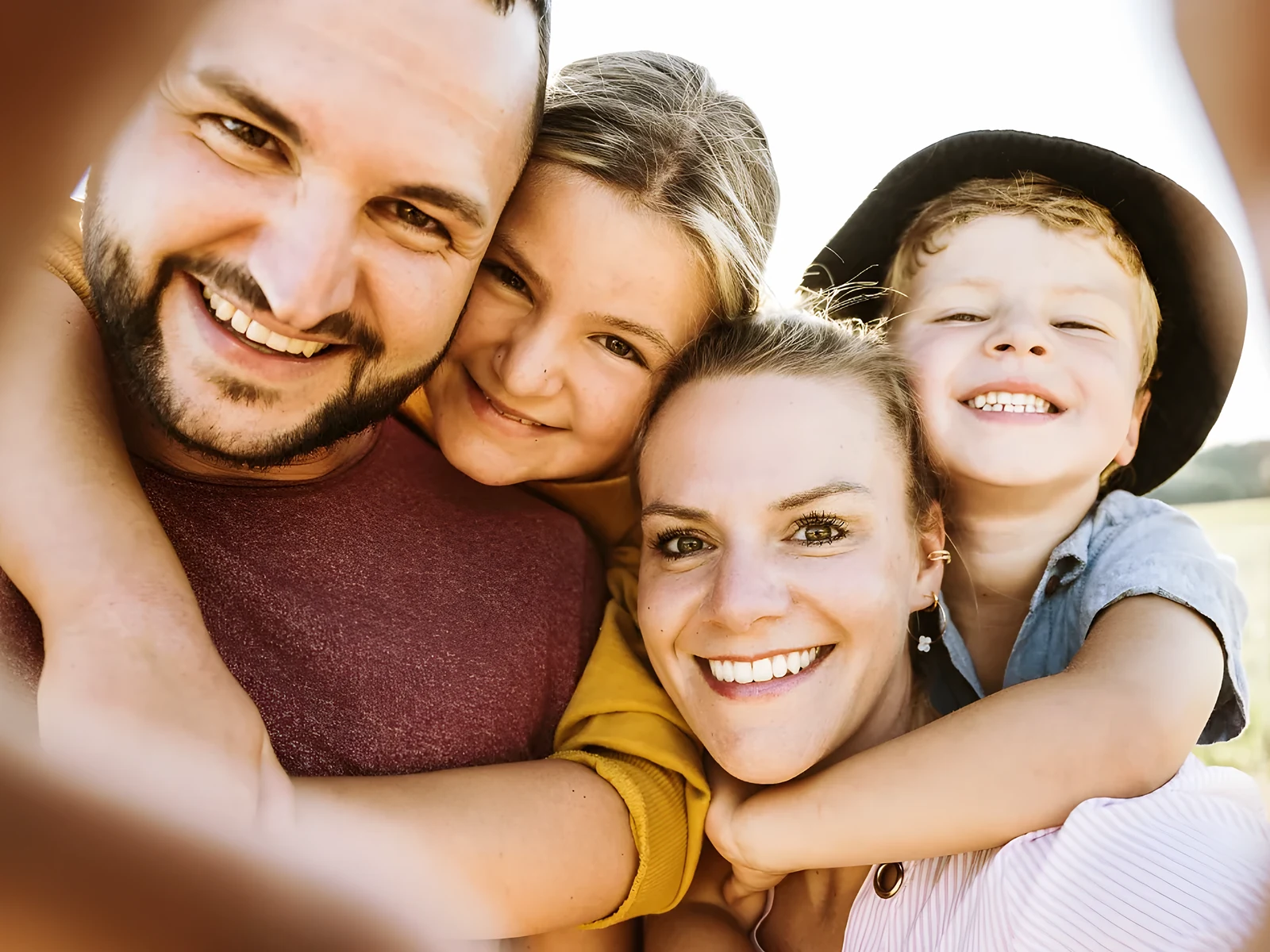 Familie mit zwei Kindern, alle lachen in die Kamera